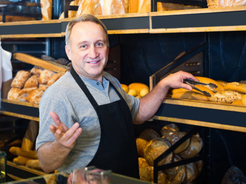 Ein Bäcker lächelt in die Kamera und nutzt Dinapay, das Kassensystem für Bäckerei und Konditorei.